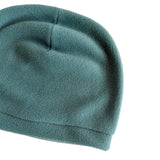A close-up of a soft fleece beanie hat in a muted teal-green color, shown against a plain white background.