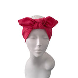 A bright red fabric headwrap with a large bow, displayed on a white mannequin head against a plain white background.