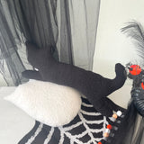 Black cat with a spider design on a white surface with black curtains in the background