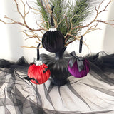 Decorative Halloween ornaments on a black vase with sheer fabric and branches in the background.