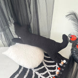 Black cat with a spider design on a white surface with black curtains in the background