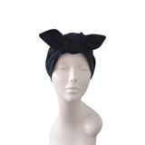 A black velvet turban headband with a large bow, displayed on a white mannequin head against a plain white background.