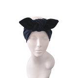 A black fabric headwrap turban hat with a large bow, displayed on a white mannequin head against a plain white background.