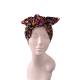 A multicolor floral-patterned fabric headwrap styled on a light pink mannequin head against a solid white background.