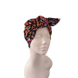 A multicolor floral print fabric headwrap turban hat styled on a light gray mannequin head against a solid white background.
