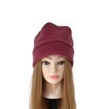 A dark red knit beanie hat displayed on a mannequin head with long light brown hair against a plain white background.