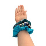 Hand wearing a blue scrunchie with colorful pattern on a white background ireland
