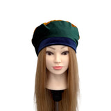 Mannequin head with a green and blue hat on a white background