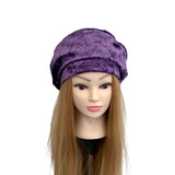 Purple velvet hat on a mannequin head with long blonde hair against a white background