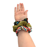 Hand wearing colorful scrunchies on a white background