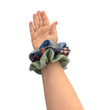 Hand wearing a stack of colorful scrunchies on a white background
