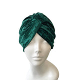 Green velvet turban on a mannequin head against a white background