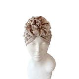 Beige headband with a floral design on a mannequin head against a white background