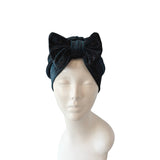 Black turban with a large bow on a mannequin head against a white background