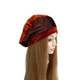 Mannequin head wearing a brown and orange hat on a white background
