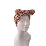 A multicolor patterned fabric headwrap turban hat styled on a white mannequin head, shown against a plain white background.