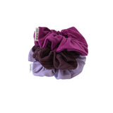 Three scrunchies in purple, brown, and lavender on a white background