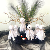 Halloween decorations with ghost figures, candy corn, and branches on a black fabric background.
