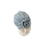 Light blue headscarf with a flower on a mannequin head against a white background