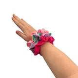 Hand wearing a colorful scrunchie on a white background