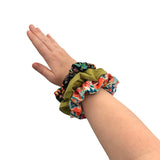 Hand wearing colorful scrunchies on a white background
