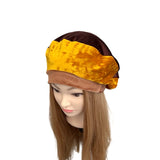 Mannequin head wearing a brown and yellow velvet headband on a white background