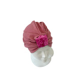 Pink headscarf with a textured square on a mannequin head against a white background