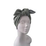 An olive green knotted fabric headwrap displayed on a matte gray mannequin head against a plain white background.