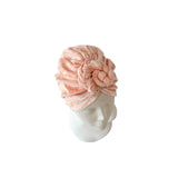 Pink headscarf with floral design on a mannequin head against a white background