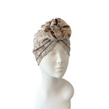 Beige patterned headscarf on a mannequin head against a white background