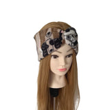 A patterned fabric headband with a twisted knot detail, displayed on a mannequin head with long light brown hair against a plain white background.