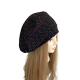 Black headscarf with pink patterns on a mannequin head against a white background