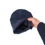 Navy blue knit beanie held by a hand on a white background