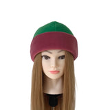 A two-tone knit beanie hat with a green top section and a burgundy bottom brim, displayed on a mannequin head with long light brown hair against a plain white background.