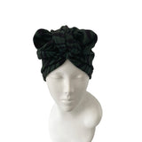 Black headscarf with a large bow on a mannequin head against a white background