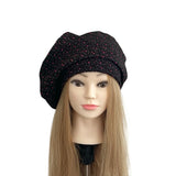 Black beret with red speckles on a mannequin head with blonde hair against a white background