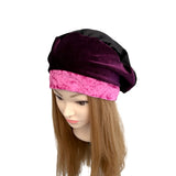 Mannequin head wearing a black and pink velvet turban on a white background