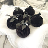 Black velvet baubles with ribbons on a white fabric background