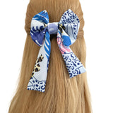 Multicolored patterned hair bow on a person's head with a plain background