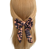 Leopard print hair bow on a person's head with a white background