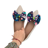Beige flats with colorful floral bow decorations on a white background