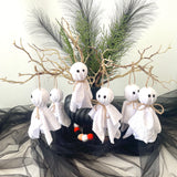 Halloween decorations with ghost figures, candy corn, and branches on a black fabric background.