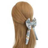 Hair bow with floral pattern on a mannequin head with brown hair against a white background