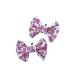 Two pink and white patterned bows on a white background