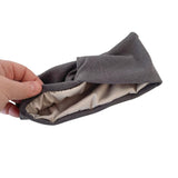 Gray fabric headband held by a hand on a white background