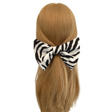 Zebra print hair bow on a mannequin head with blonde hair against a white background