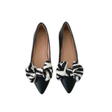 Black pointed-toe shoes with zebra-patterned bows on a white background