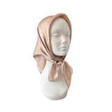 Mannequin head wearing a beige satin headscarf on a white background