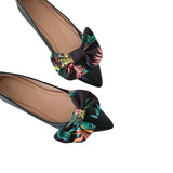 Black flats with floral bow details on a white background