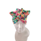 A multicolor floral knotted headwrap turban hat displayed on a white mannequin head against a plain white background.